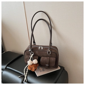 Detailed macro view of vintage brown suede Boston bag featuring buckle pockets and plush bear charm