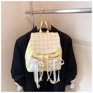 Close-up of yellow plaid backpack featuring a delicate white lace bow detail