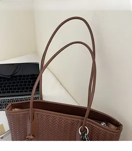 Détail de la texture tressée et de la bandoulière confortable du sac cabas marron