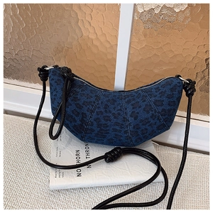 Detail of blue denim crescent bag featuring black leopard print and knotted leather strap