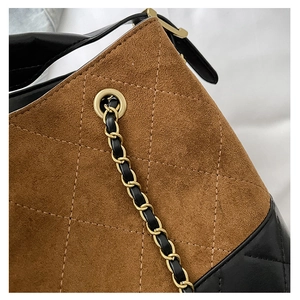 Macro view of brown suede stitching and gold chain leather strap detail on tote bag