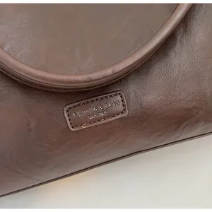 Close-up of dark brown leather texture with detailed stitching and embossed fashion logo