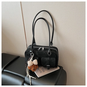 Close-up of black suede Boston bag with silver buckles and a cute teddy bear charm