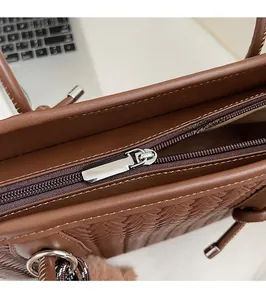 Détail de la fermeture éclair en métal argenté et texture en cuir tressé du sac marron