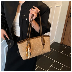 Detail of khaki quilted tote bag with vintage beaded charm and retro faux suede texture