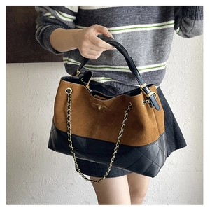 Close-up of dual-texture tote bag featuring brown suede and black quilted leather details