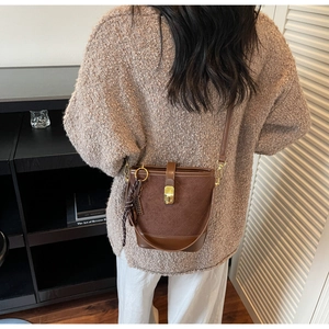 Detail of a brown quilted bucket bag with a decorative silk scarf and gold hardware