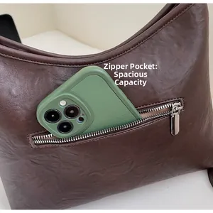 Close-up of the back zipper pocket of a brown leather bag showing spacious storage for a phone