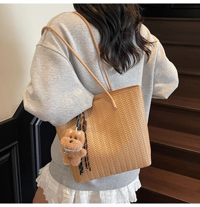 Close-up of brown woven tote bag with leather texture and cute plush puppy keychain charm