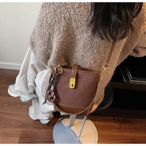 Detailed close-up of dark brown bucket bag featuring quilted suede and heart butterfly charm