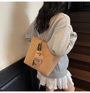 Dettaglio della borsa tote intrecciata marrone vintage con ciondolo a forma di orsetto
