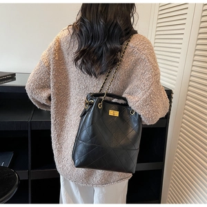 Close-up of black quilted suede bucket bag with gold chain strap and twist-lock detail