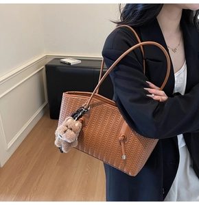 Détail du cabas tressé marron avec fines lanières et pendentif chiot en peluche