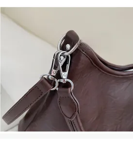 Close-up of vintage dark brown wrinkled leather handbag with shiny silver hardware hooks