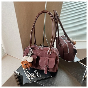 Detail of burgundy suede Boston bag with double pockets and cute plush bear charm
