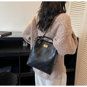 Model wearing a black quilted leather bucket bag with gold chain strap for daily commuting