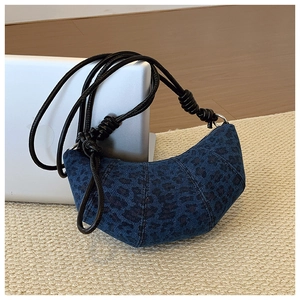 Detailed close-up of dark blue leopard print denim croissant bag with leather strap