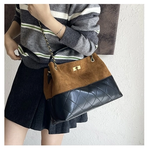Detail of vintage suede tote bag with quilted leather pattern and gold chain strap