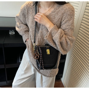 Close-up of black quilted bucket bag with golden twist lock and brown pretzel charm