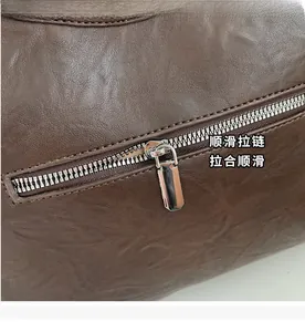 Close-up detail of smooth silver metal zipper on textured dark brown leather bag