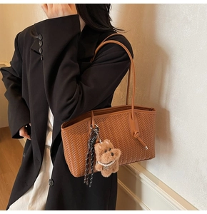 Détail du sac cabas tressé marron avec bandoulière en cuir et breloque chiot en peluche