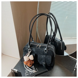 Detail of vintage black suede Boston bag with utility pockets and teddy bear charm