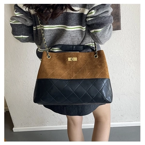 Detail of suede and quilted leather texture with gold chain strap and metal turn-lock