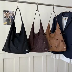 Detail of laser-cut floral pattern on faux suede hobo tote bags in three colors