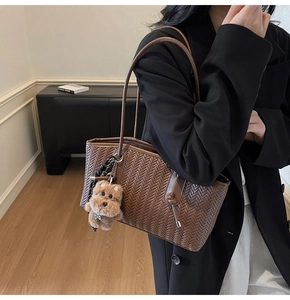 Détail du sac cabas marron en cuir tressé avec breloque de chiot en peluche mignonne