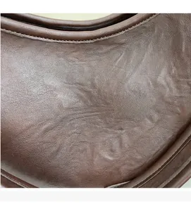 Close-up of deep brown leather texture with neat stitching on casual crossbody bag