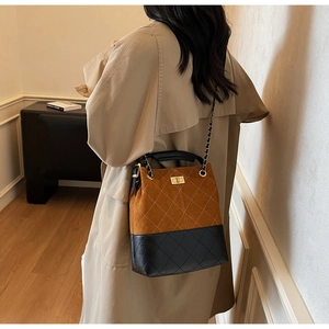 Detail of vintage quilted suede bucket bag with metal turn-lock and chain strap
