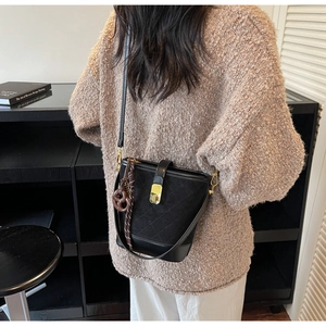Detail of black quilted suede bucket bag with gold twist lock and pretzel charm detail