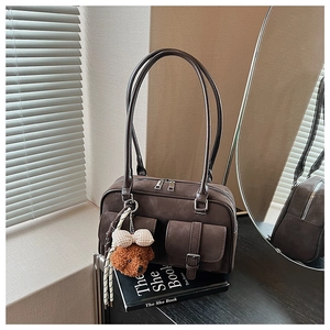 Detail of dark brown vintage Boston bag featuring buckle pockets and a teddy bear charm