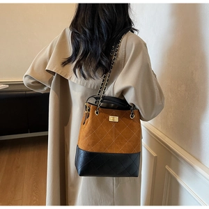 Detail of color-block bucket bag with diamond quilting and metallic chain strap