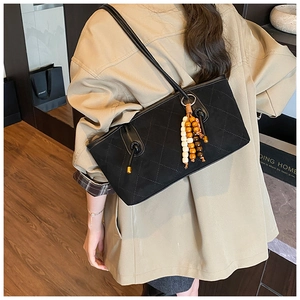 Detail of black quilted tote bag with vintage wooden beads charm on a shoulder strap