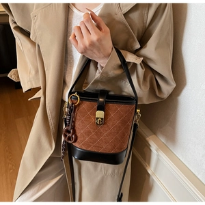 Detail of vintage quilted suede bucket bag with contrast leather and pretzel charm