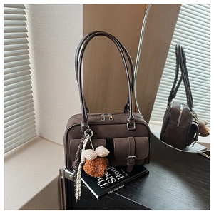 Detail view of coffee brown suede retro Boston bag with plush bear charm and pockets