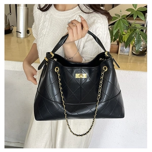 Detail of black quilted leather tote bag featuring gold twist lock and chain strap