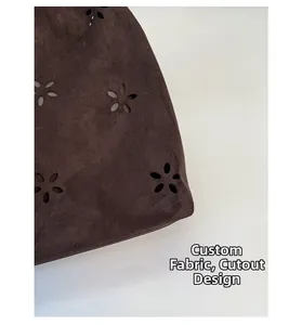Detail of laser-cut hollow floral pattern on high-quality brown suede shoulder bag