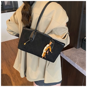 Close-up of black quilted suede shoulder bag with retro wooden bead tassel detail