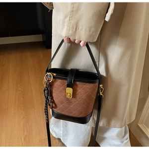 Close-up of brown quilted bucket bag with gold clasp and textured suede finish
