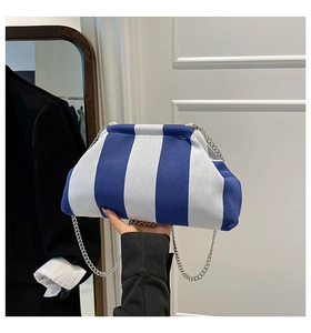 Dettaglio della borsa a conchiglia in tela a righe bianche e blu con catena e chiusura magnetica