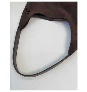 Detail view of smooth leather handle and laser-cut petal design on suede tote bag
