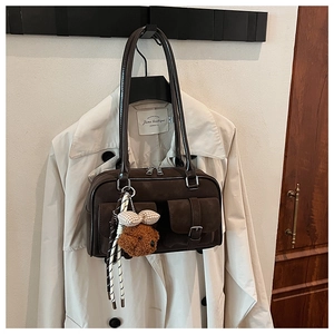 Detail of vintage brown suede shoulder bag with dual pockets and plush teddy bear charm