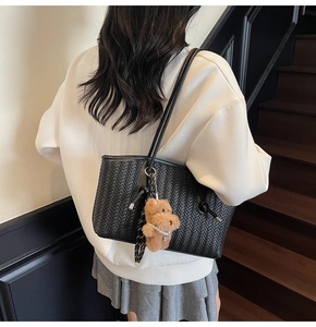 Détail d'un grand sac cabas noir tissé avec pendentif ours en peluche marron