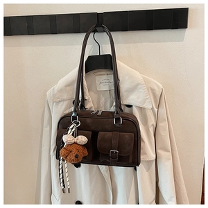 Detail of dark brown matte Boston bag with front pockets and plush puppy charm