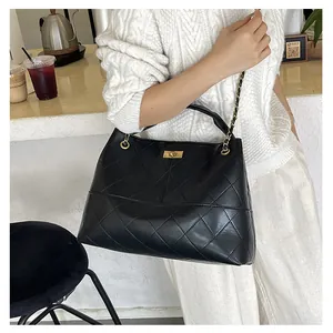 Close-up of a large black quilted leather tote bag with a golden turn-lock on the shoulder