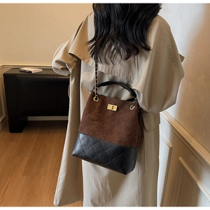 Detail of color-block suede bucket bag with quilted stitching and gold chain strap