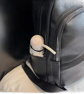 Detail of the black pebbled leather backpack side pocket with a white folding umbrella