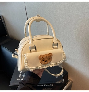 Detail of cream white PU pillow bag featuring a fuzzy bear patch and lace trim